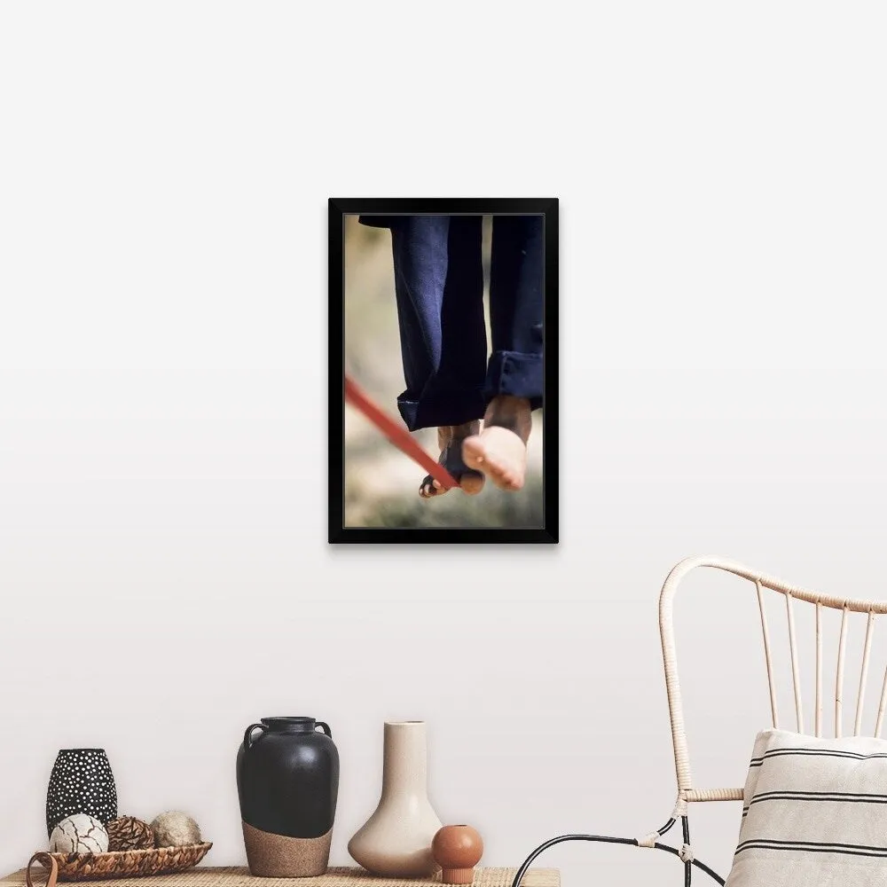 "Close up of a man's bare feet balancing on a slackline in the California desert." Black Framed Print